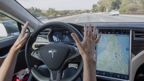 Photo de conducteur utilisant l'autopilot Tesla, les mains au dessus du volant.