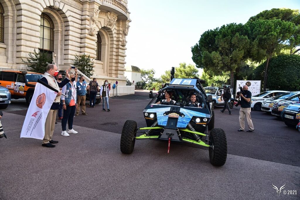 Départ du Rallye Aïcha des Gazelles 2021 à Monaco, devant le Prince Albert II de Monaco, qui agite le drapeau et salue les participantes.