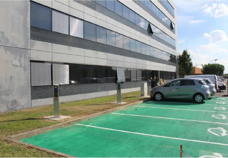 Places de stationnement réservées à la recharge, au pied d'un immeuble de bureaux