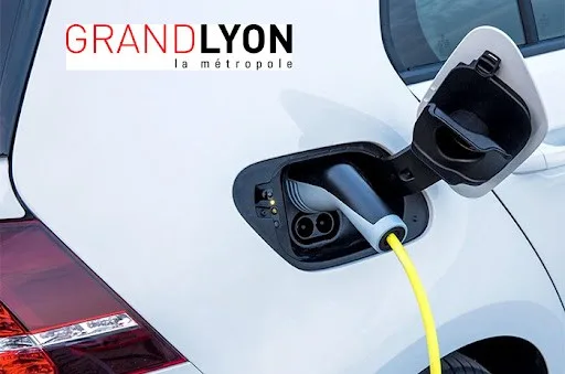 Photo en gros plan d'un véhicule électrique du "Grand Lyon La Métropole" et de sa prise de recharge