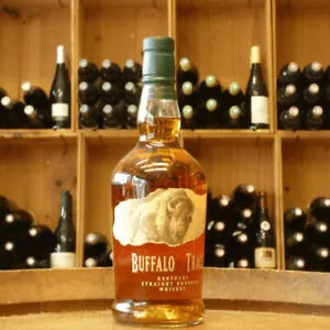 Bouteille de Buffalo Trace Straight Bourbon, devant un présentoir d'autres vins et spiritueux.