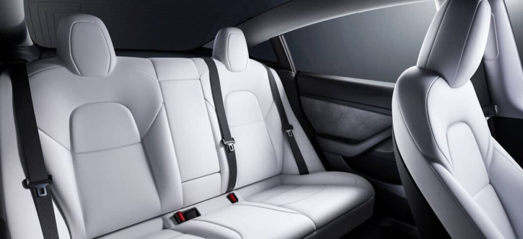 Photo commerciale des sièges arrière de la Tesla Model 3, de couleur blanche.