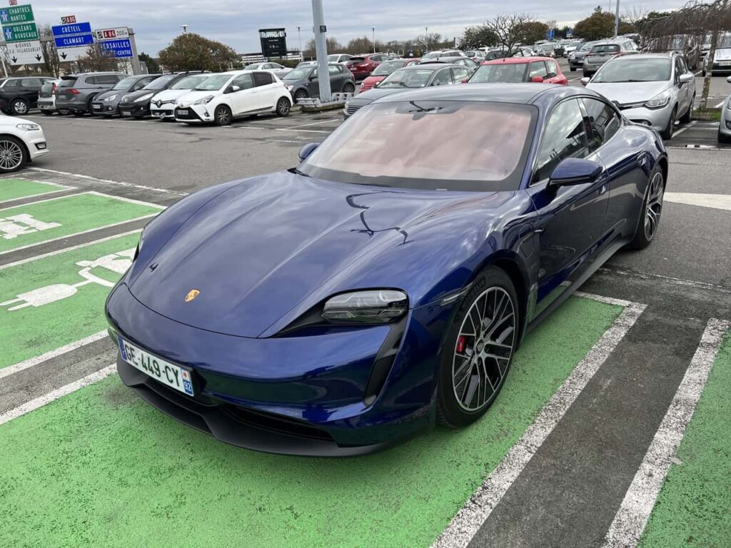 Porsche Taycan tentant de se garer sur une place de parking de la station Izivia, à Velizy2