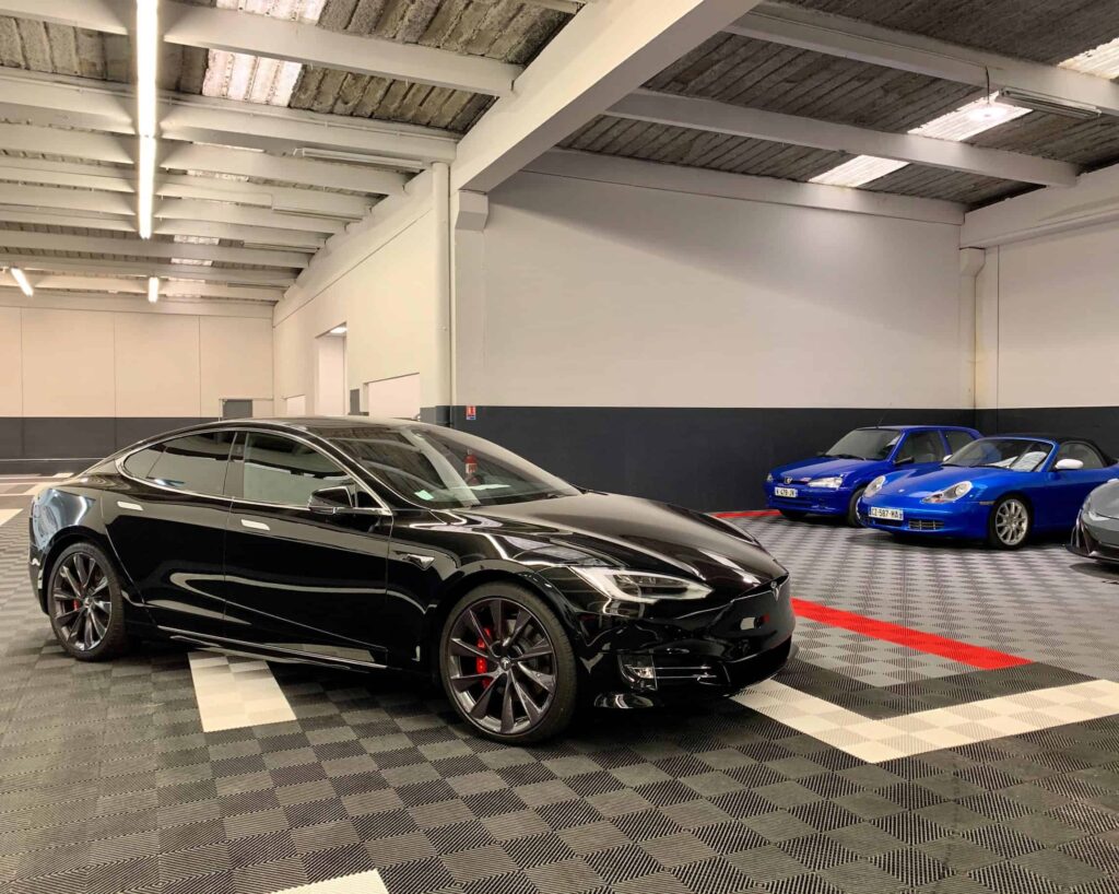 Photo de véhicules dans le garage d'Auto Detailing Reims, avec une Tesla de couleur noire au premier plan
