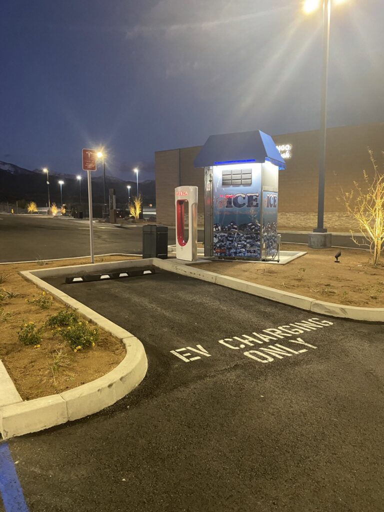 Photo d'une place de supercharger à côté de laquelle est installé un stand portant la mention "ICE"