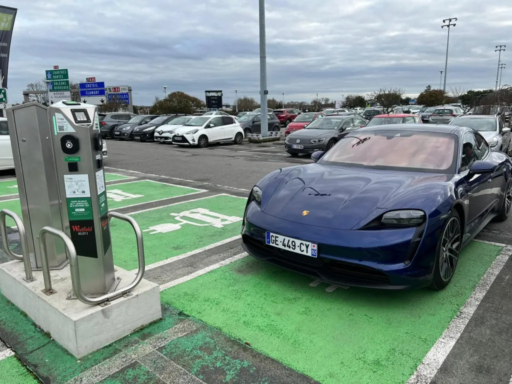 Porsche Taycan garée sur une place devant une borne de recharge
