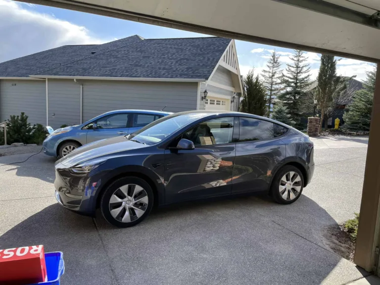 Tesla Model Y grise garée devant une maison