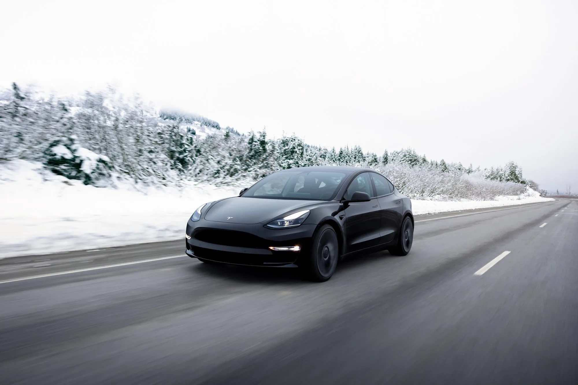 Tesla Model 3 noire sur route enneigée