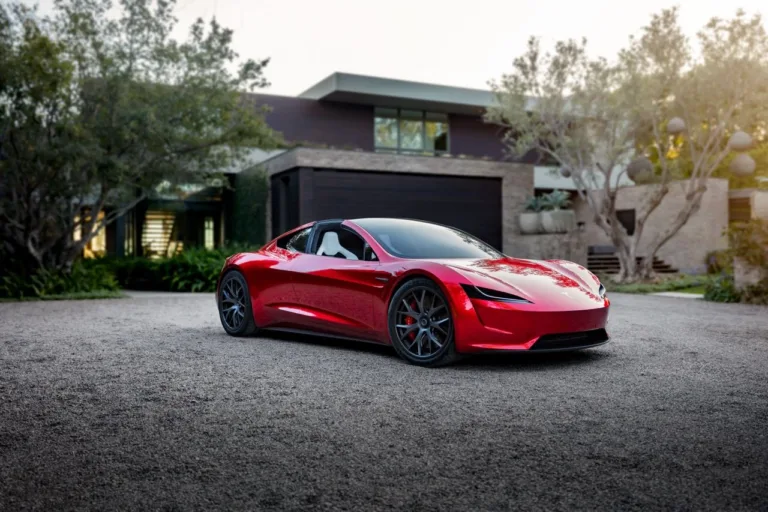 Tesla Roadster rouge garé devant une maison contemporaine