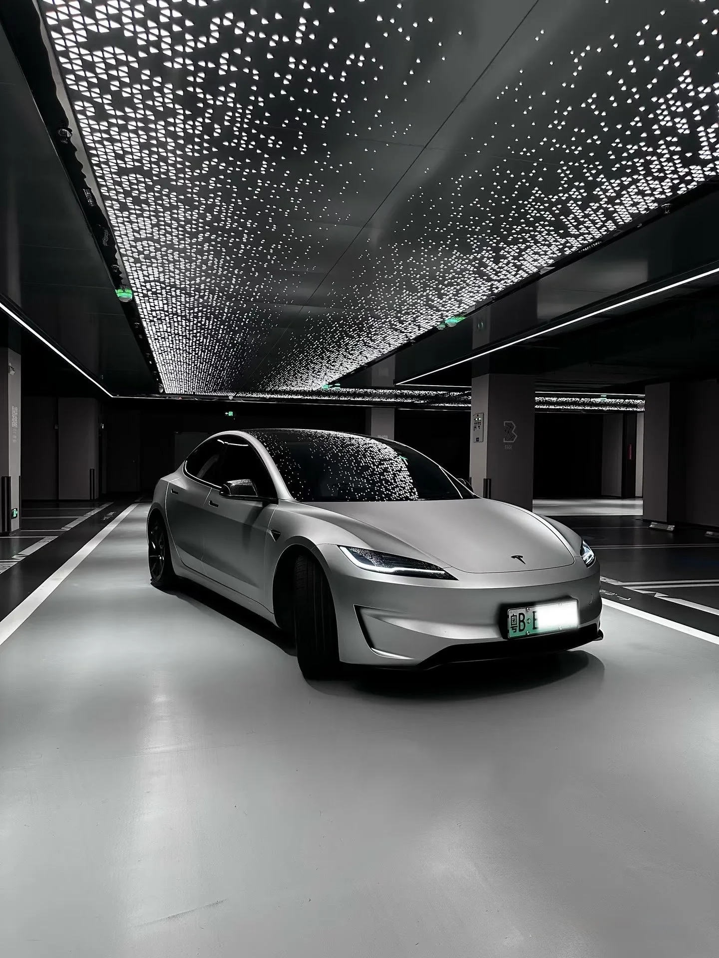 Tesla Model 3 Performance grise sous un plafond lumineux étoilé