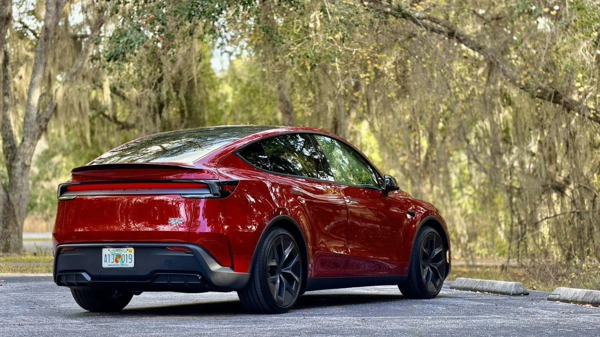 Tesla Model Y Performance rouge vue de l'arrière, sous les arbres