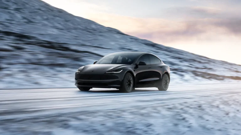 Tesla Model 3 noire roulant sur une route enneigée