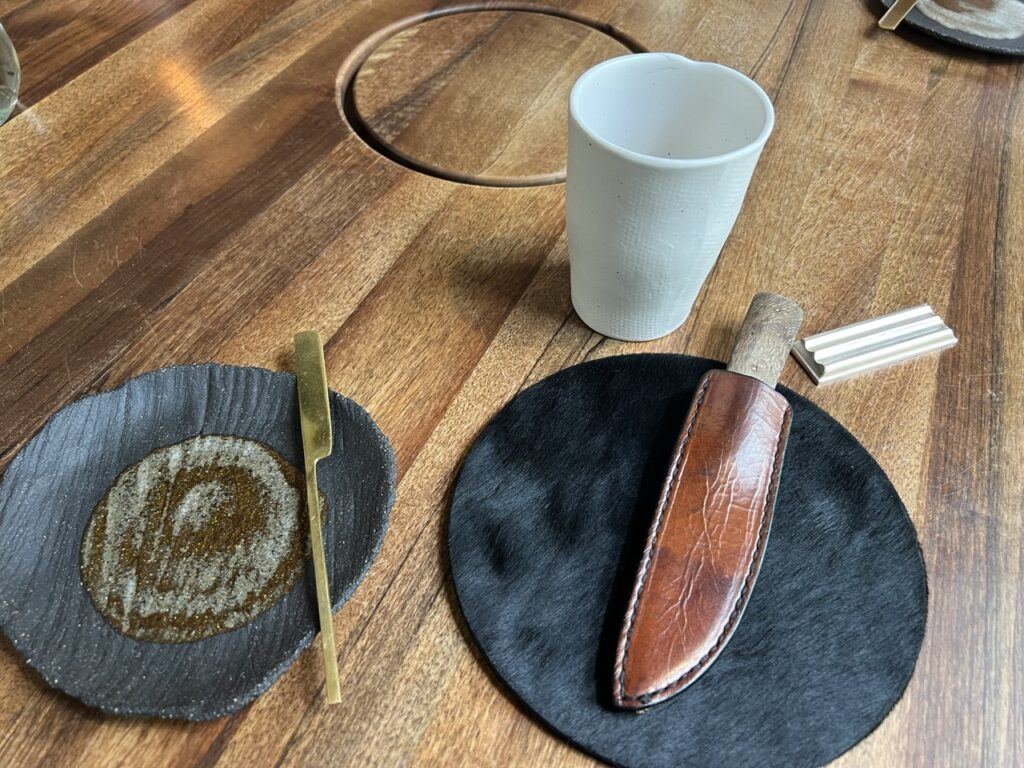 Couvert du restaurant L’Ours : set rond noir, couteau dans un étui en cuir, assiette à pain