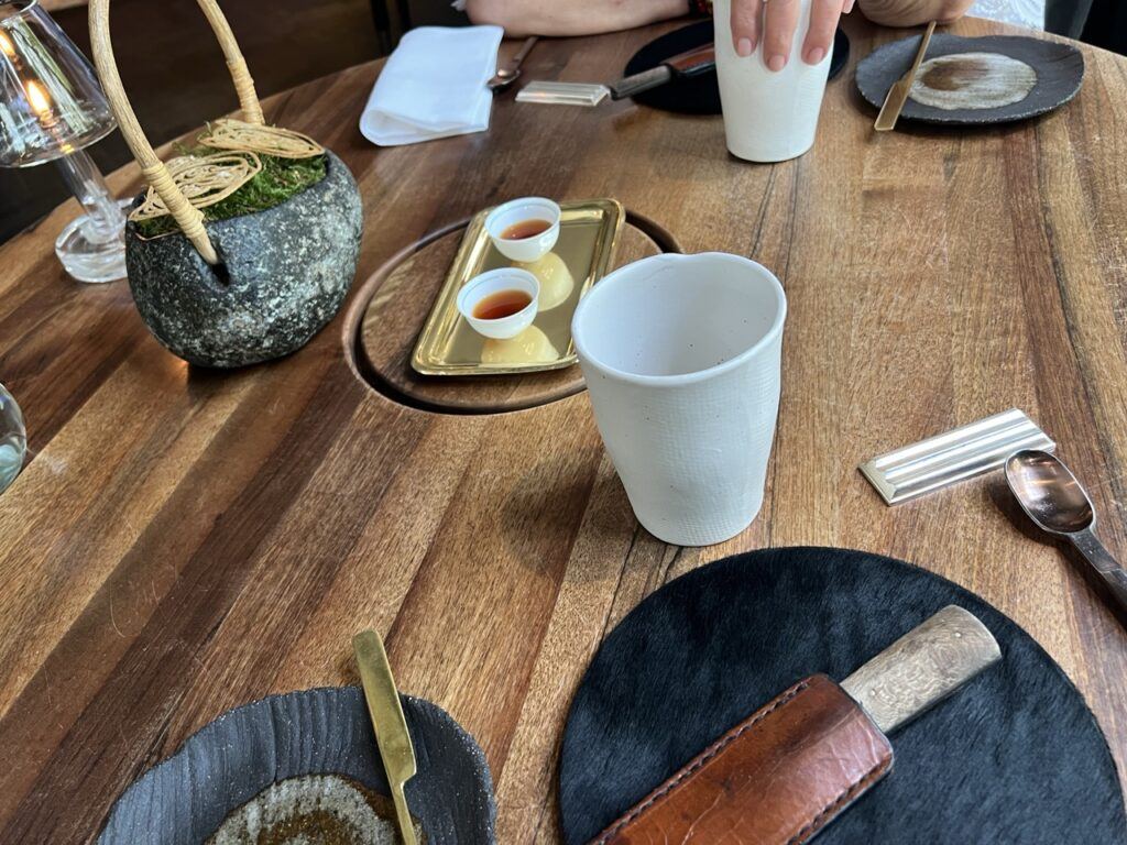 Bouchées d’accueil servies dans un pot de pierre garni de mousse et sur un plateau doré