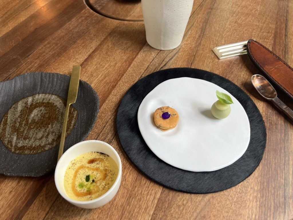 Sablé au parmesan et bille de concombre au basilic sur une assiette blanche