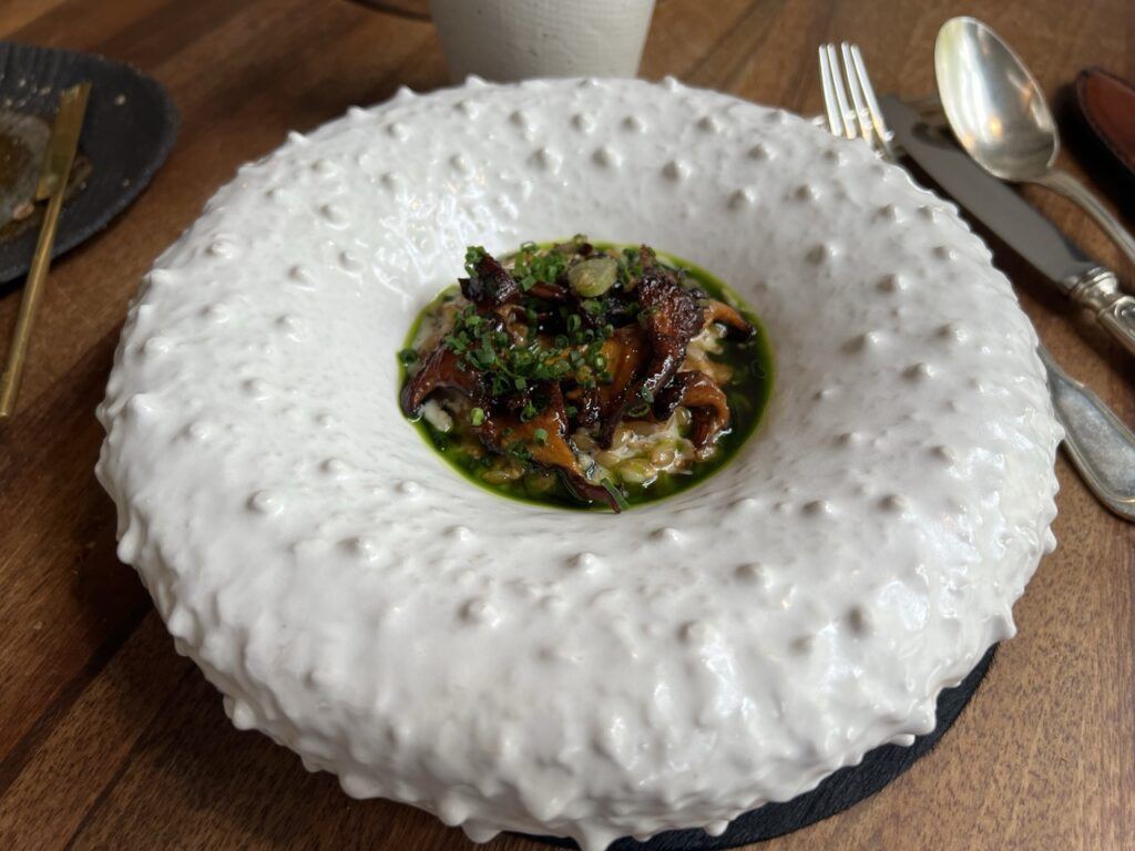 Risotto de petit épeautre aux girolles et au shiso dans une grande assiette blanche en relief