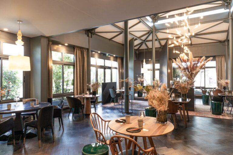 Salle du restaurant L’Ours sous sa verrière, avec sculpture lumineuse et fleurs séchées