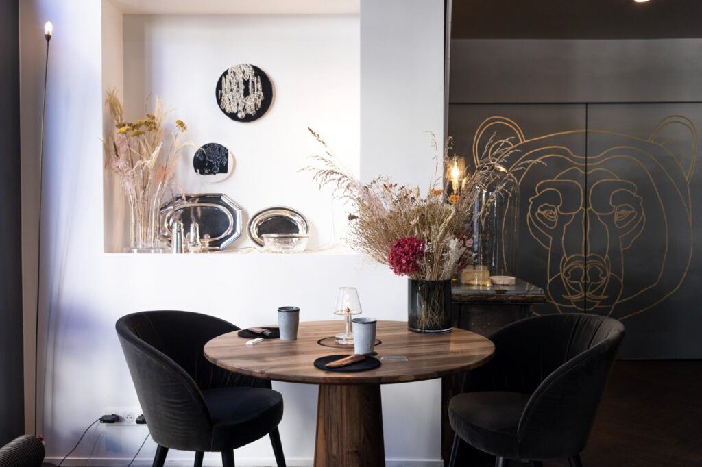 Table ronde en bois et fauteuils noirs devant un ours dessiné en doré sur un mur sombre