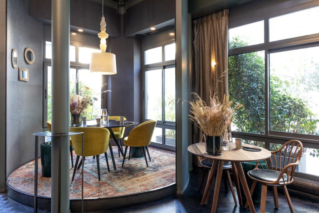 Tables du restaurant L’Ours devant de grandes baies vitrées ouvertes sur la verdure