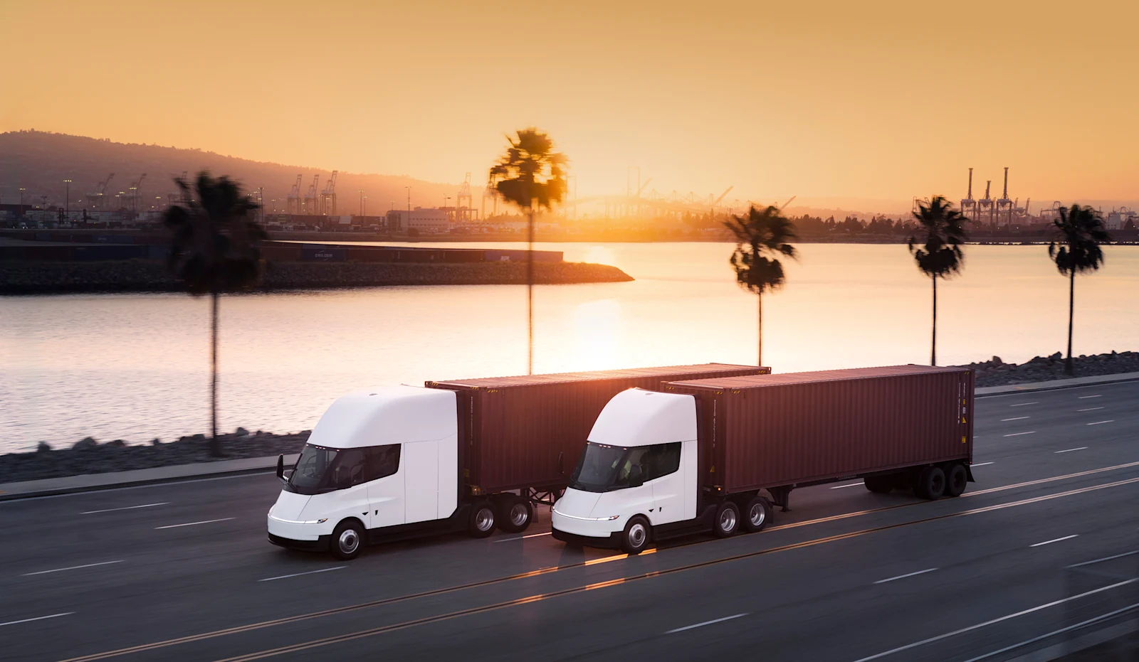 Deux Tesla Semi tractant des conteneurs sur une route côtière