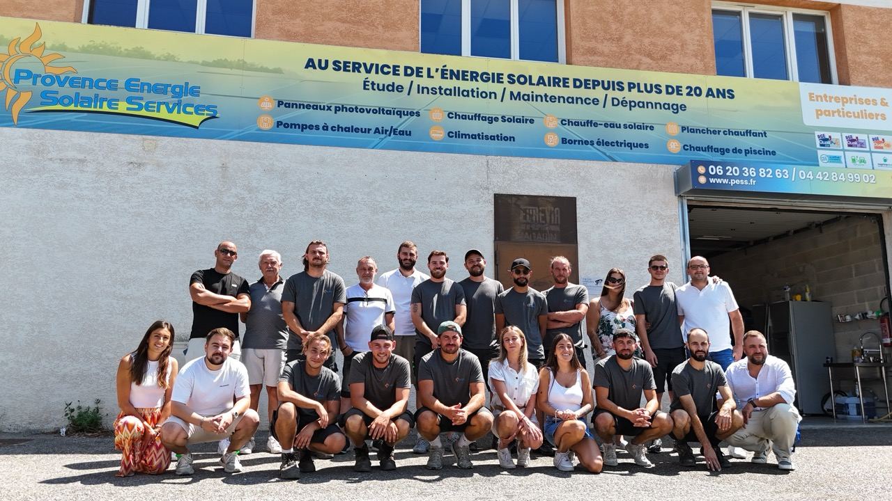 Groupe posant devant le siège de Provence Énergie Solaire Services, à La Ciotat, sous l’enseigne « Au service de l’énergie solaire depuis plus de 20 ans »