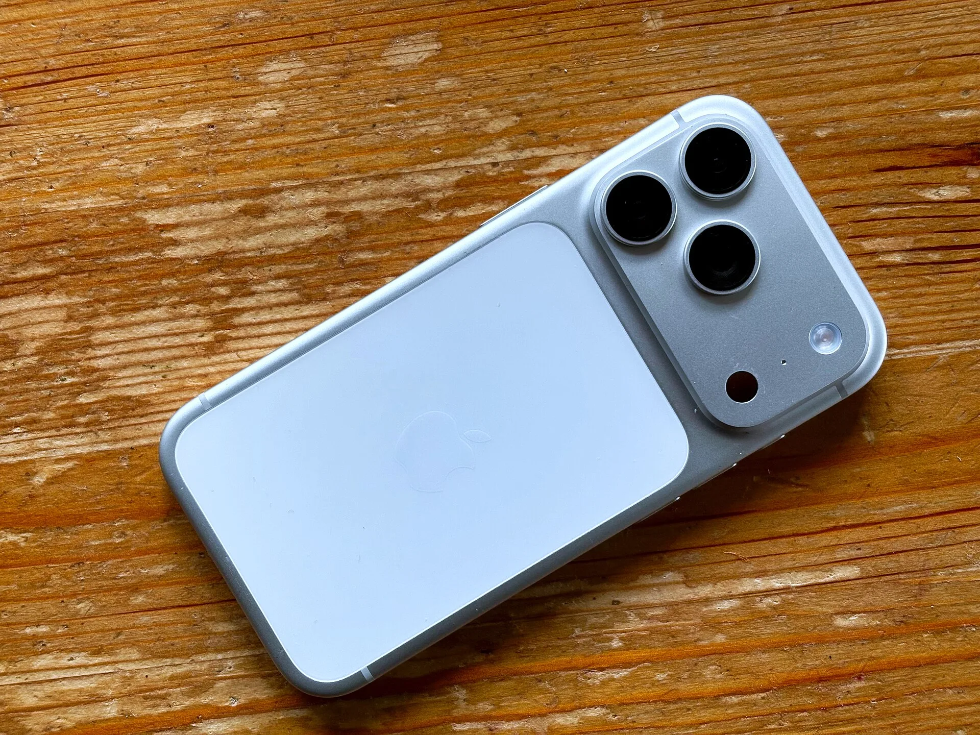Un iPhone 17 Pro blanc posé sur une table en bois