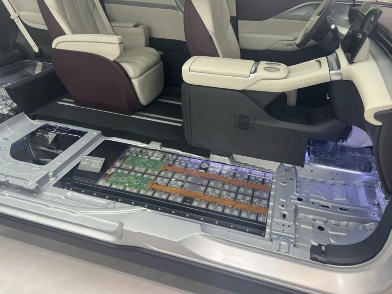 Un châssis de voiture électrique et sa batterie présentés en coupe sur un stand du salon de Pékin