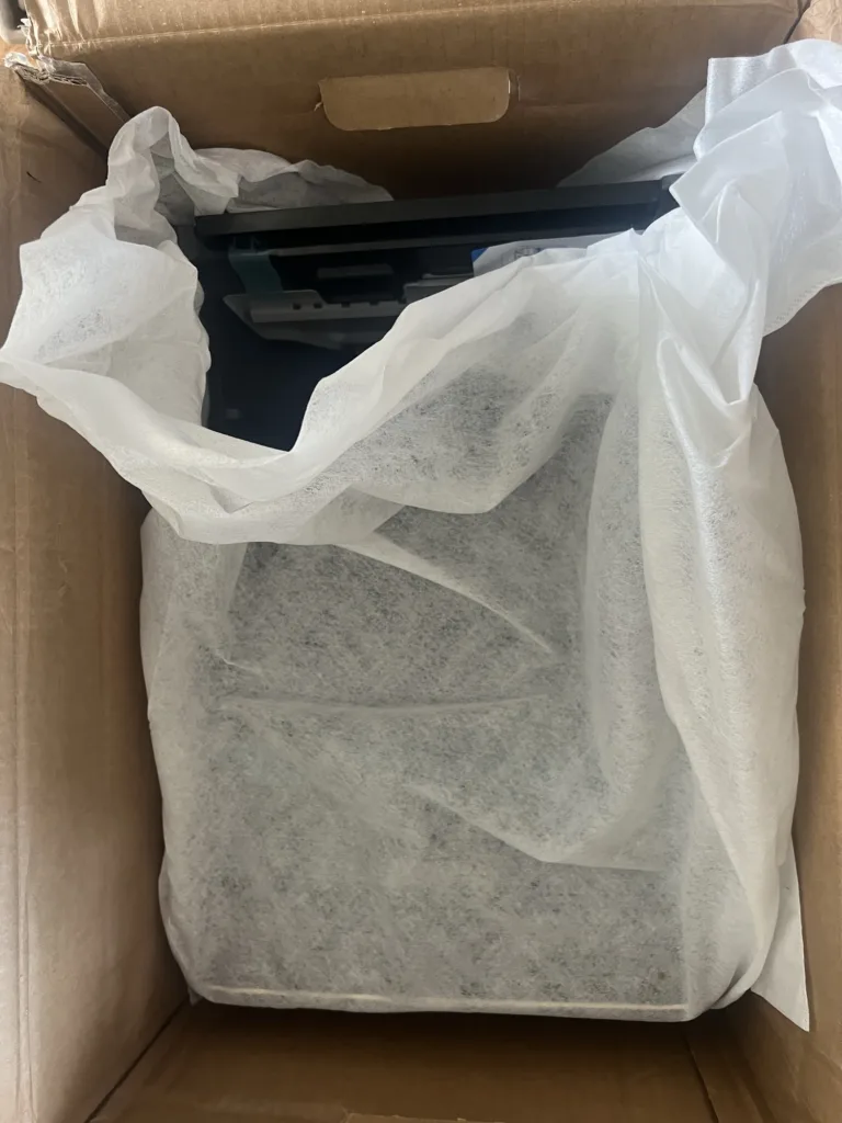 La station du DEEBOT T90S sous sa housse de protection, dans le carton