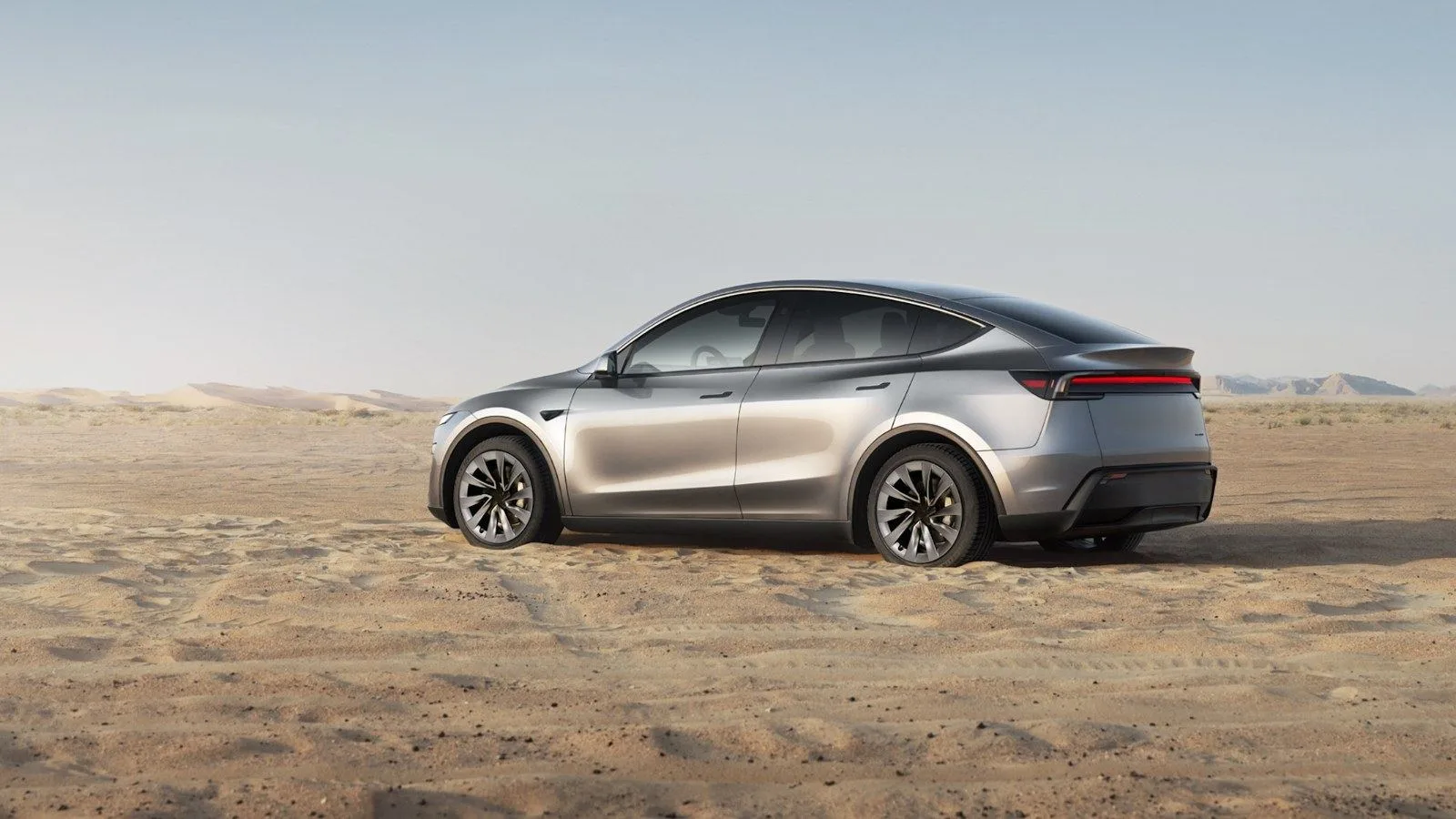 Tesla Model Y gris argent vu de profil sur un terrain sec