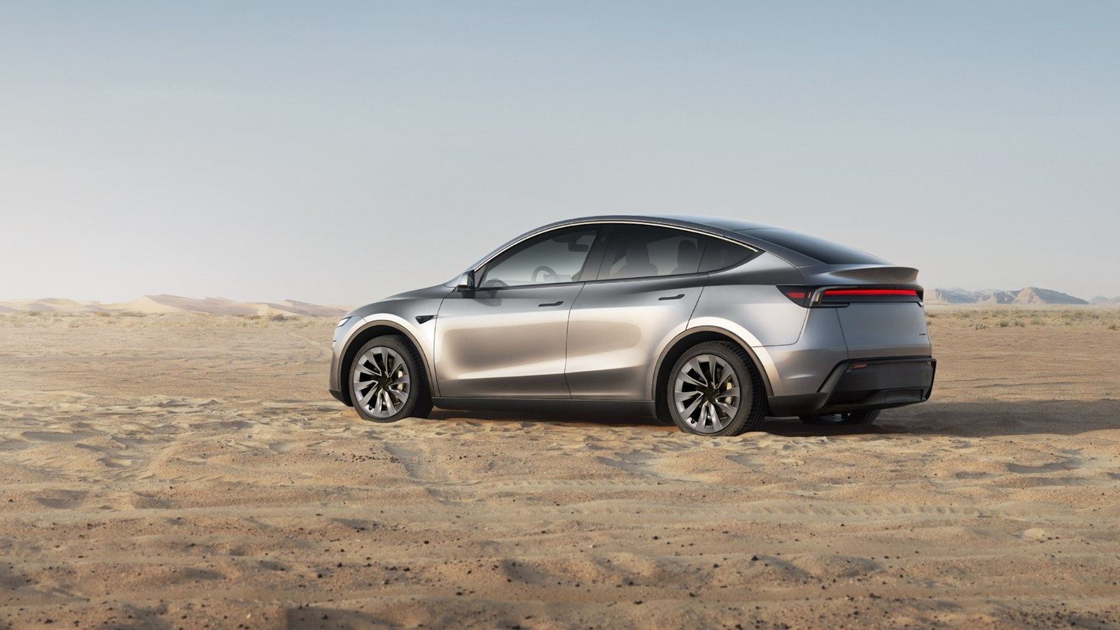 Tesla Model Y gris argent vu de profil sur un terrain sec
