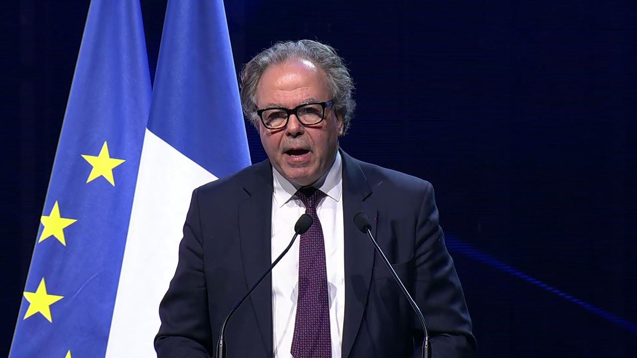 Luc Chatel, président de la PFA, au pupitre du Paris Automotive Summit 2026 devant les drapeaux français et européen