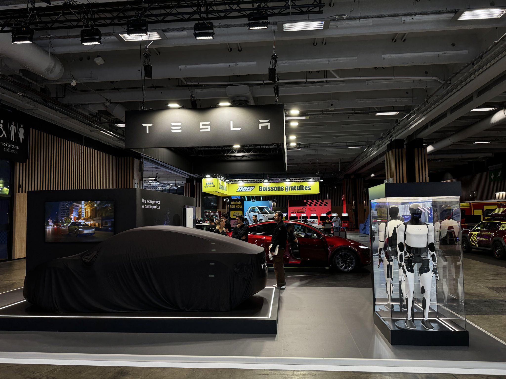 Le stand Tesla au Mondial de l'Auto 2026 à Paris, avec le Cybercab encore bâché et le robot Optimus en vitrine