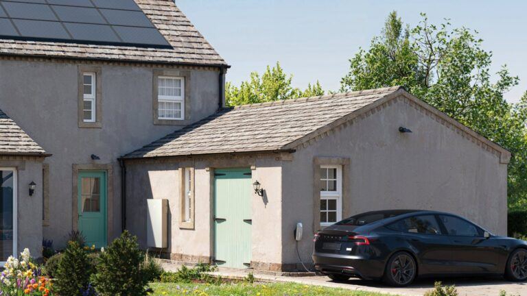 Maison avec panneaux solaires, batterie Powerwall 3 et voiture Tesla garée devant