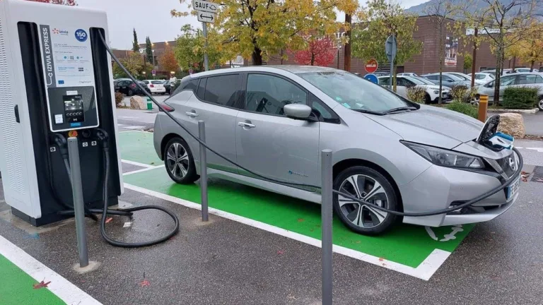 Voiture électrique en charge sur une borne rapide Izivia, sur une place de parking peinte en vert