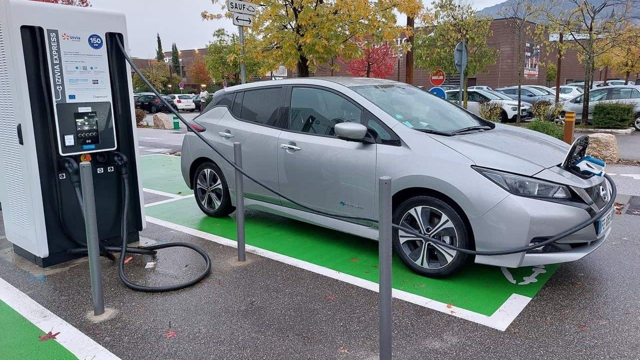Voiture électrique en charge sur une borne rapide Izivia, sur une place de parking peinte en vert