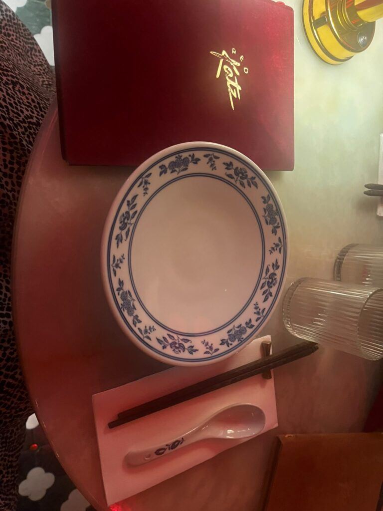 Table dressée chez Red Katz : carte rouge brodée, assiette de porcelaine bleue et blanche