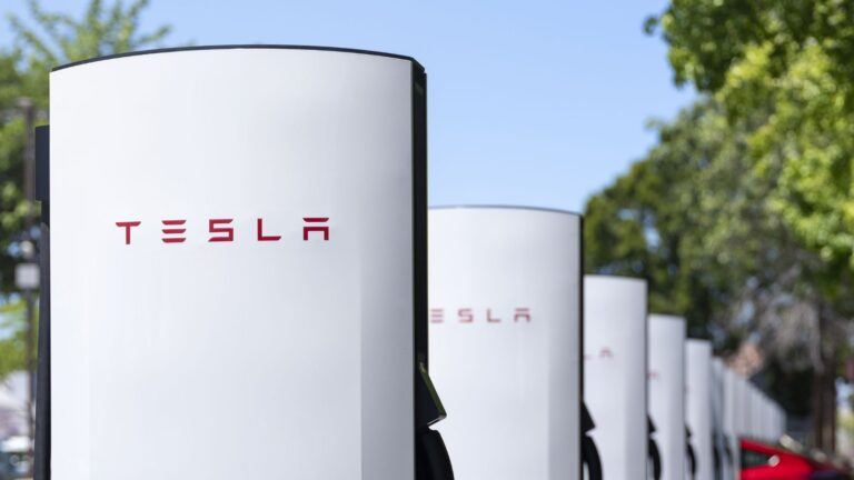 Une rangée de Superchargeurs Tesla V4 sur un parking arboré