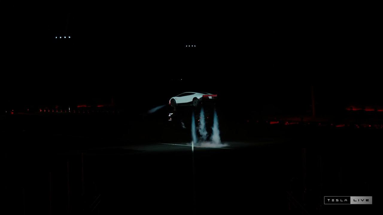 Le Tesla Roadster en vol stationnaire au-dessus de la piste, propulseurs dirigés vers le sol